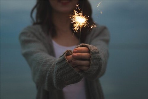 Woman in a sweater holding a sparkler